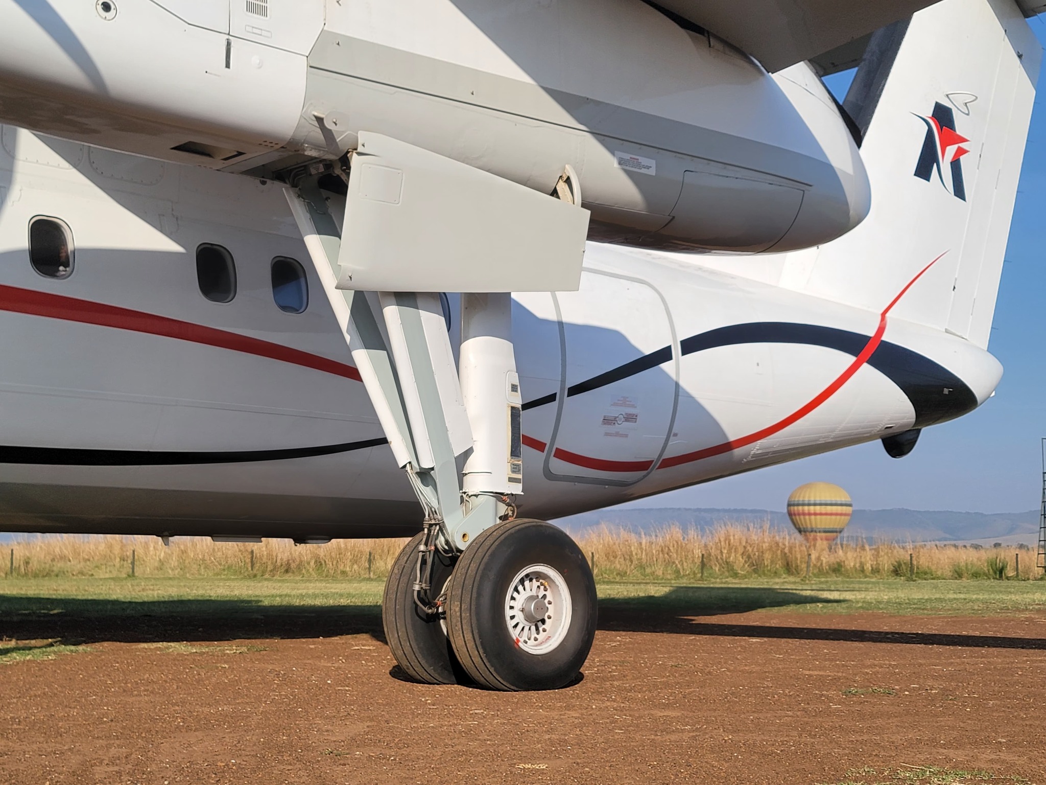 Light aircraft parked on a red earth airstrip