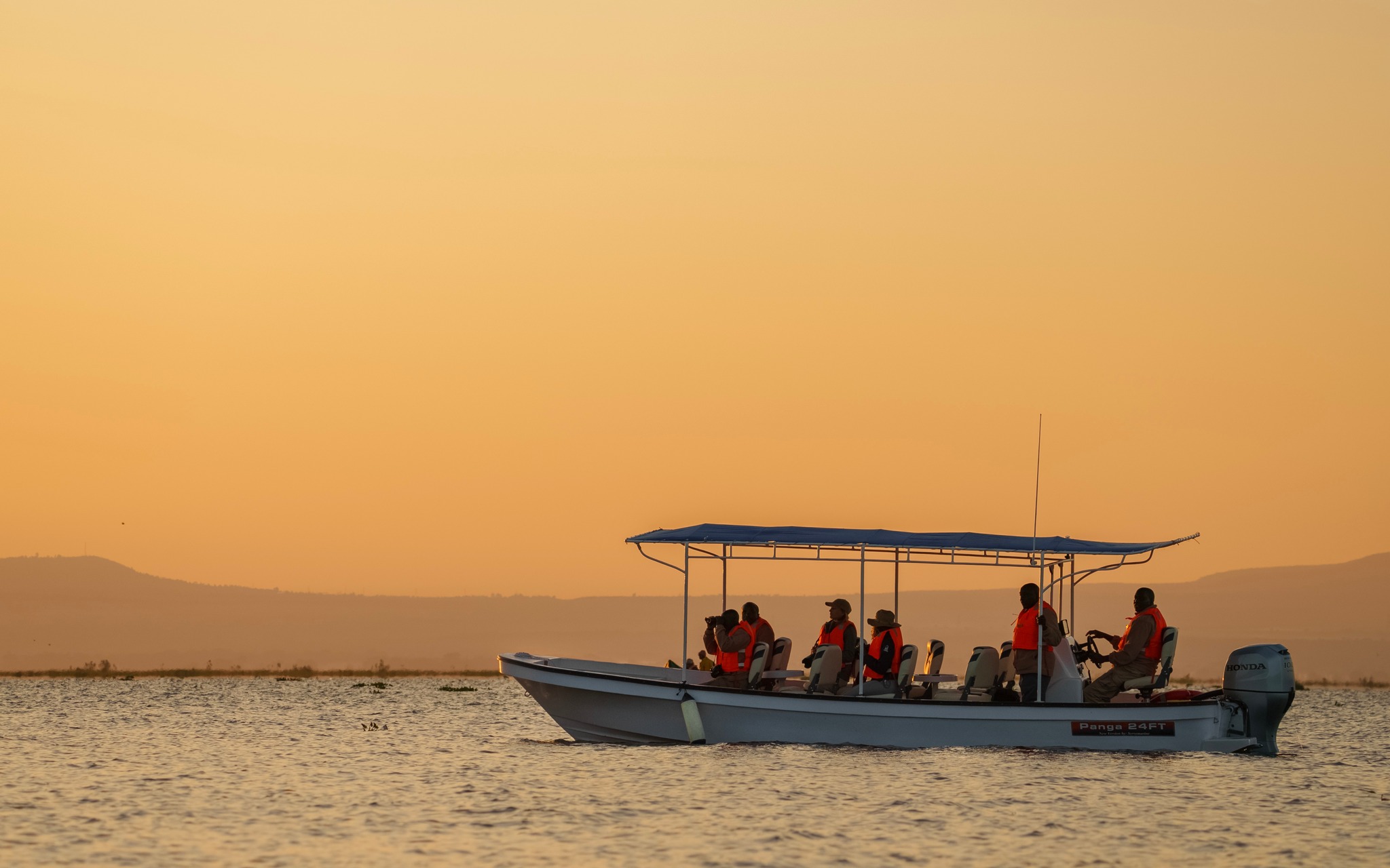 Boat carrying passengers on a lake at sunset
