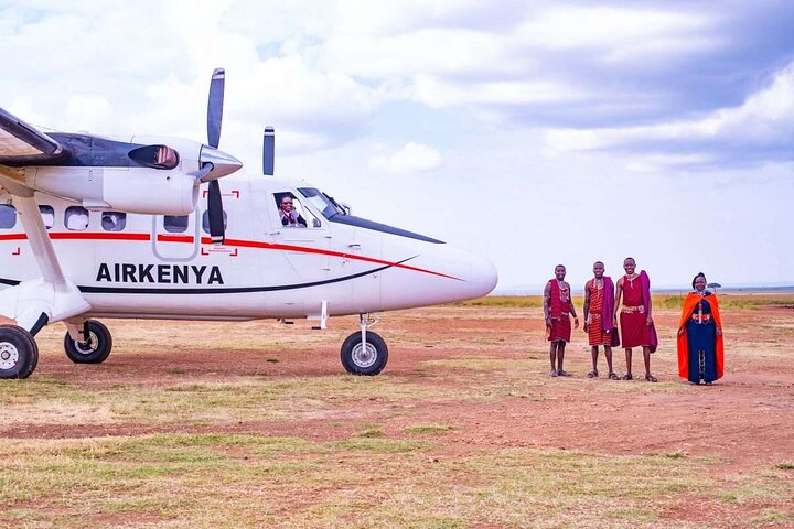 Light aircraft on a bush airstrip with Maasai men waiting