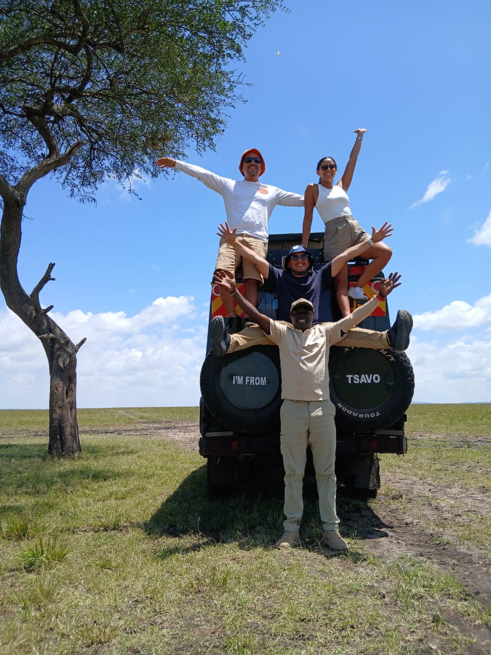 Group of guests standing on a safari vehicle with arms raised