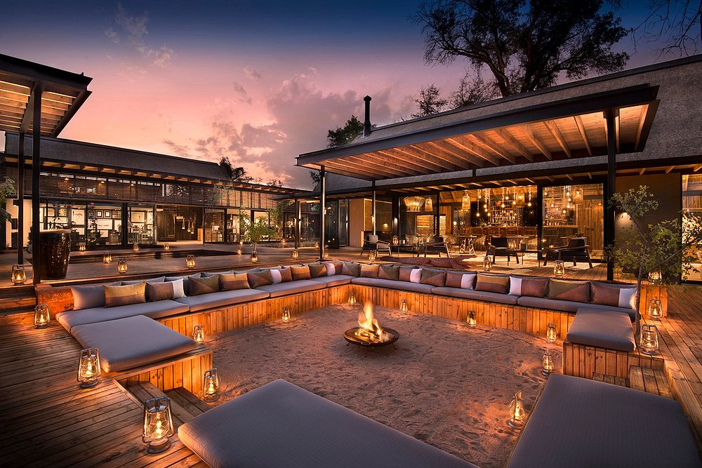 Safari lodge lit at dusk beside a swimming pool